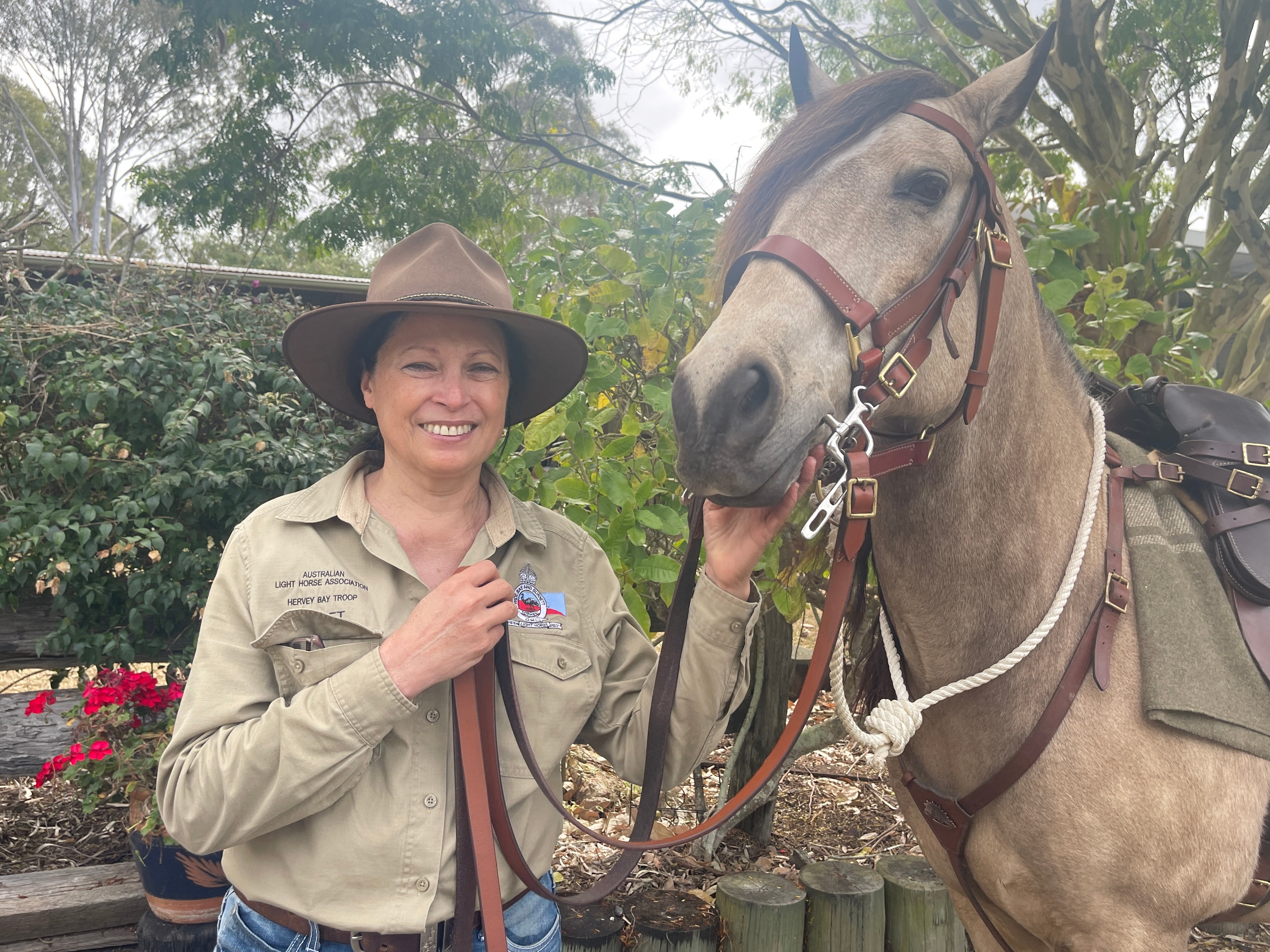A horse trainer smiles proudly while wrangling her beloved equine pet.