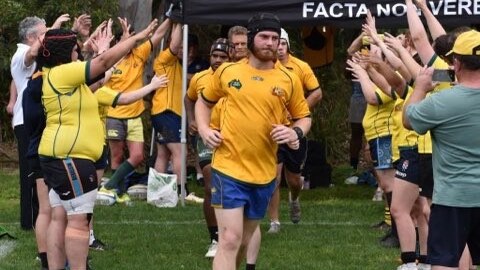 Man in rugby uniform running onto a field.