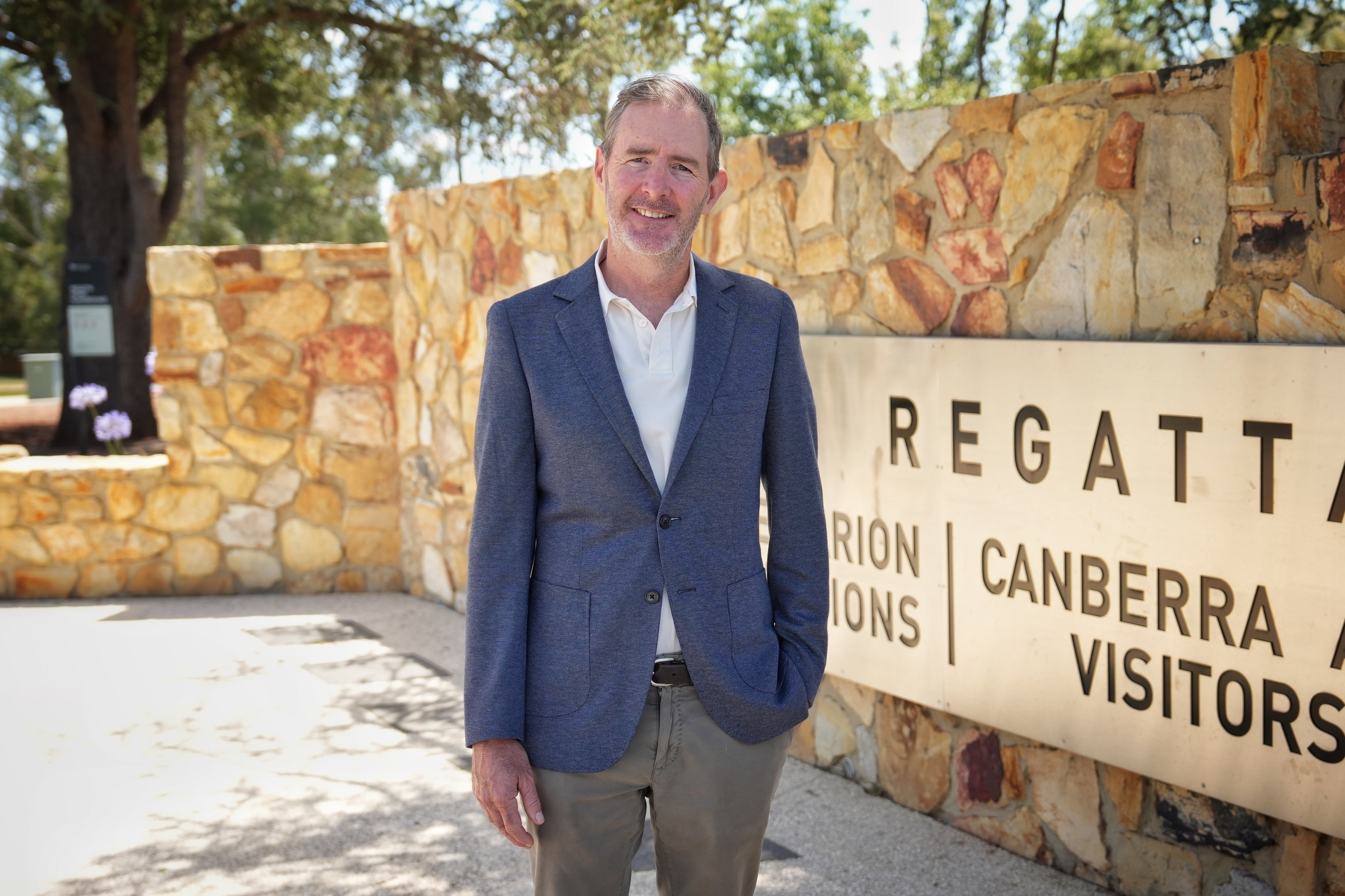 Um homem veste terno e sorri com calma.