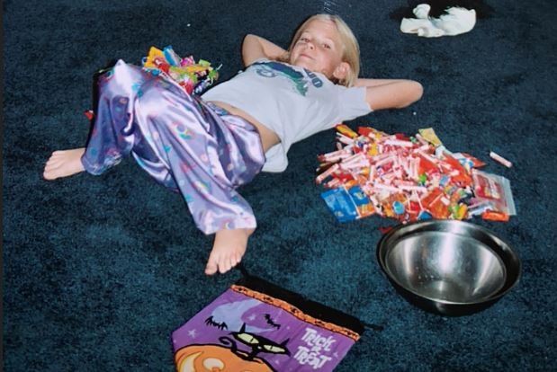 A young girl lays on the floor surrounded by lollies