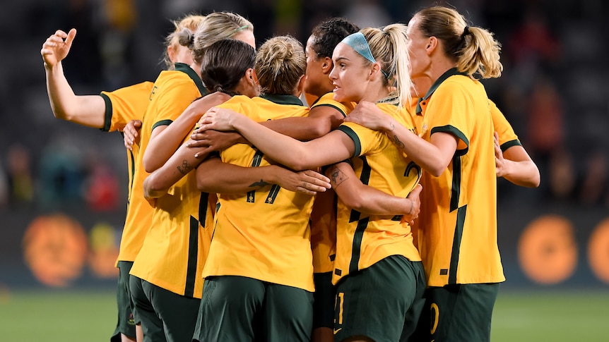 Female soccer players huddle after scoring a goal during a match