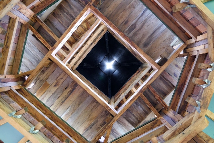 A hexagonal wooden structure with sunlight visible in the center. 
