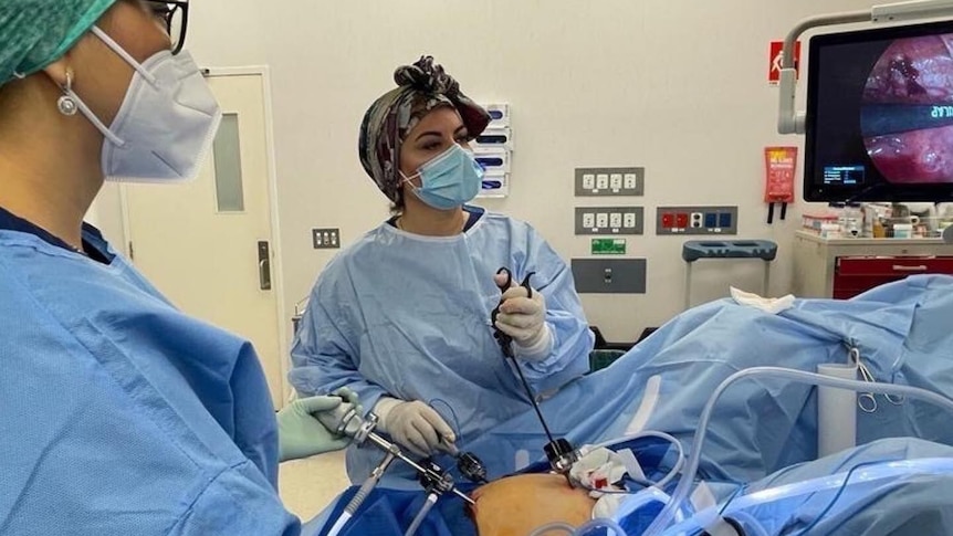 A female doctor performing a surgery in an operating theatre. 