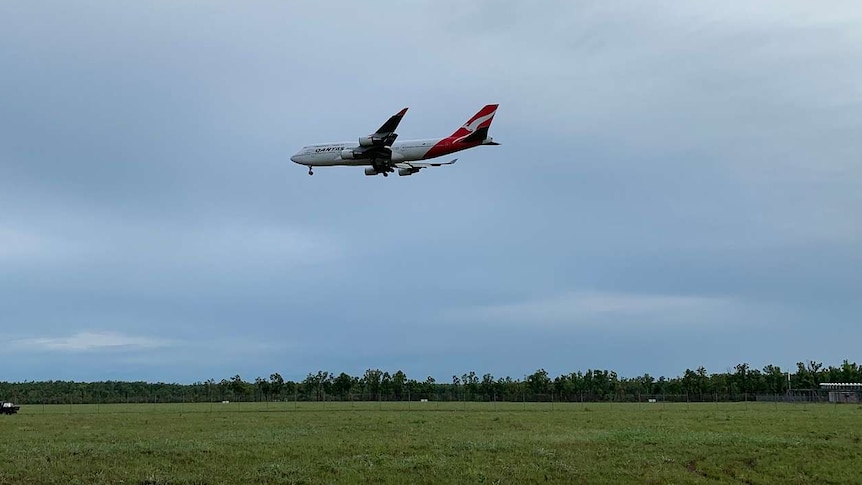 A Qantas p[lane carrying coronavirus evacuees descends into Darwin.