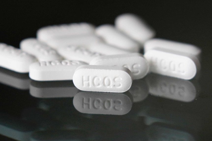 Hydroxychloroquine tablets are displayed on a dark surface