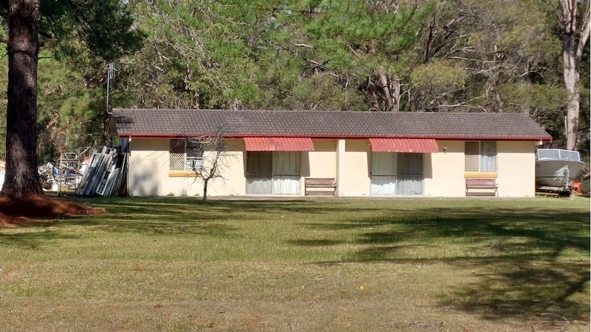 An outside view of a small single-storey country motel, with a grass lawn at the front.