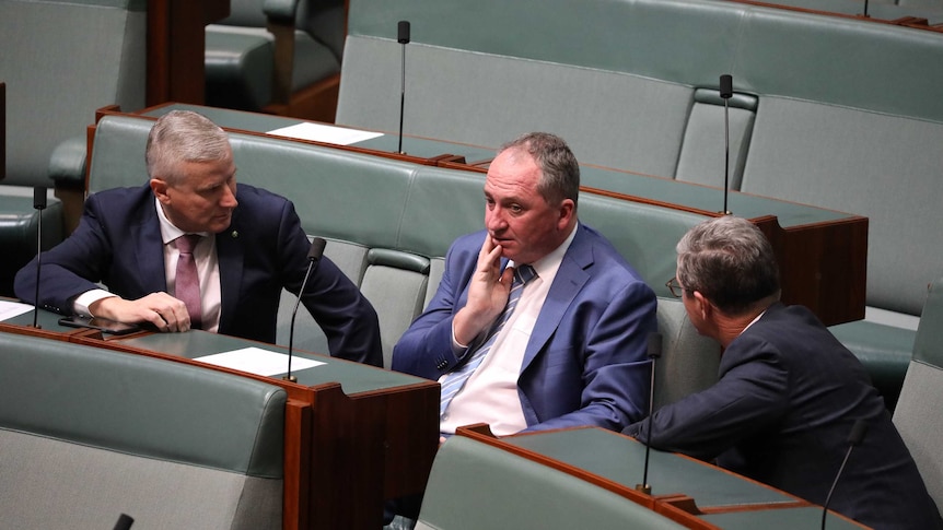 Three men sitting on government benches deep in coversation