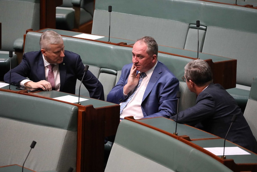 Three men sitting on government benches deep in coversation