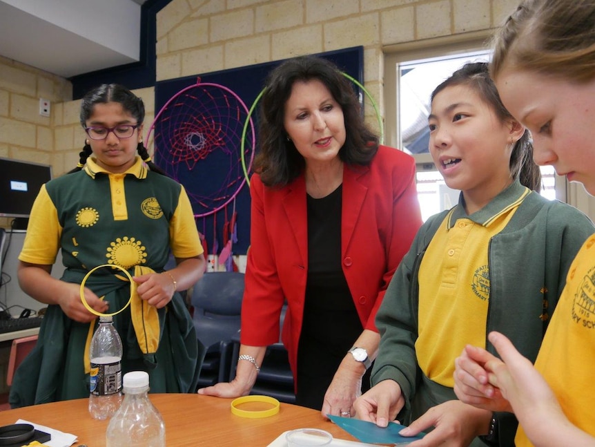 A group of primary school students and their principal in a classroom.