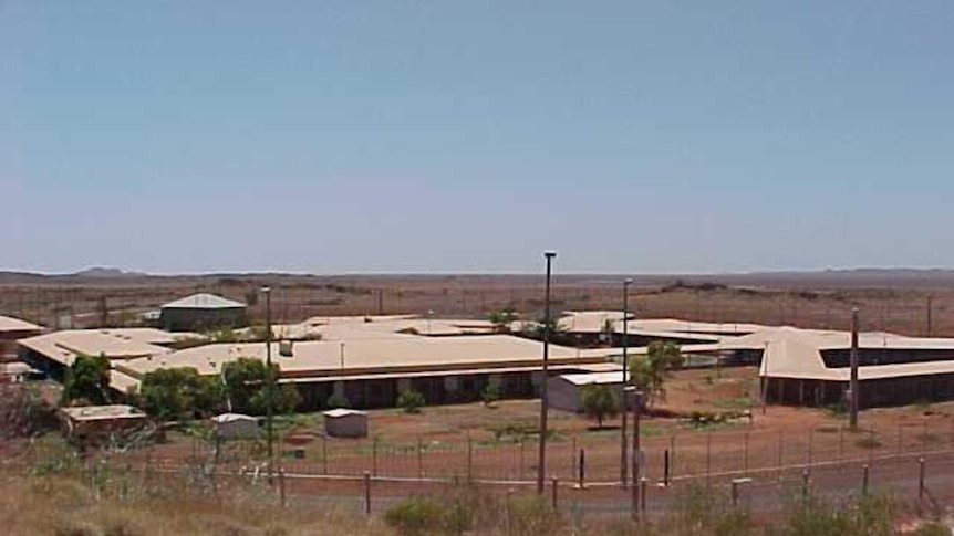 Wide shot of Roebourne prison under blue sky with fences and buildings clearly showing