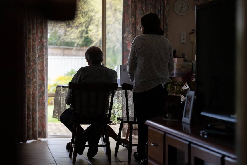 A man and woman inside a house with their backs to the camera.