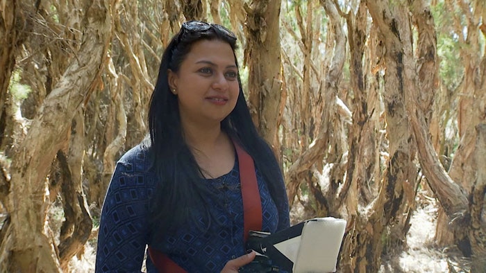 Woman with camera around neck on strap in bushland