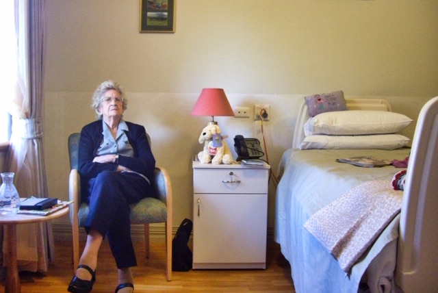 An older woman in a nursing home looking confused.