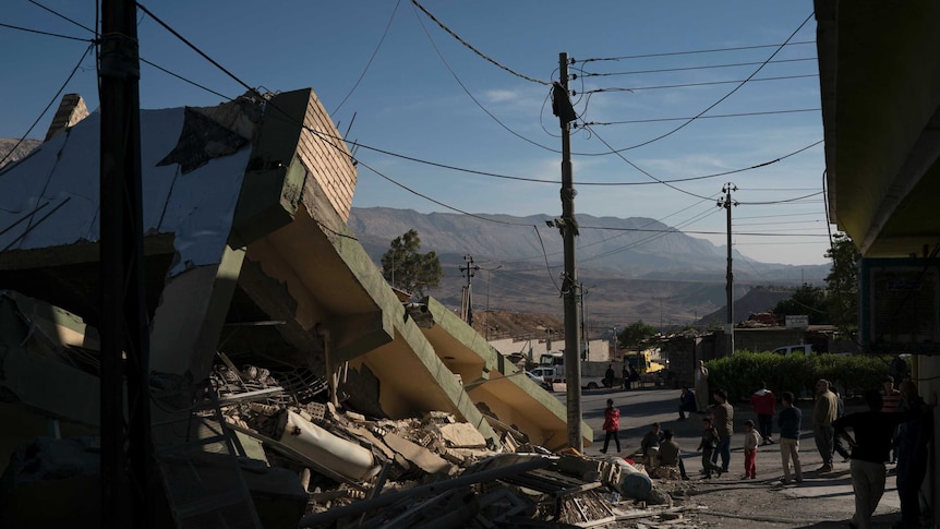 People walk next to a destroyed house after an earthquake in the city of Darbandikhan (Photo: AP/Felipe Dana)