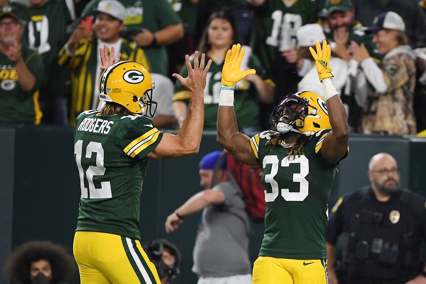 Arron Jones and Aaron Rodgers hold their hands up above their heads
