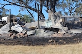 A messy pile of corrugated silver sheets of steel on blackened ground.