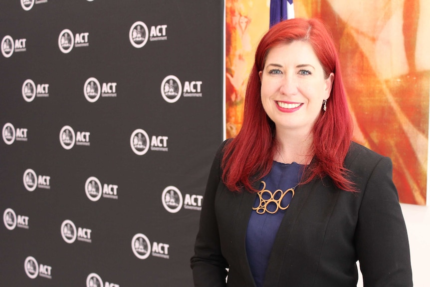 A women with long bright red hair smiles.