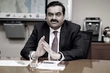 Gautam Adani holds his hands together at a meeting.