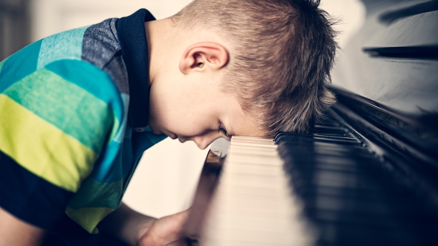 Child banging head on keyboard of piano