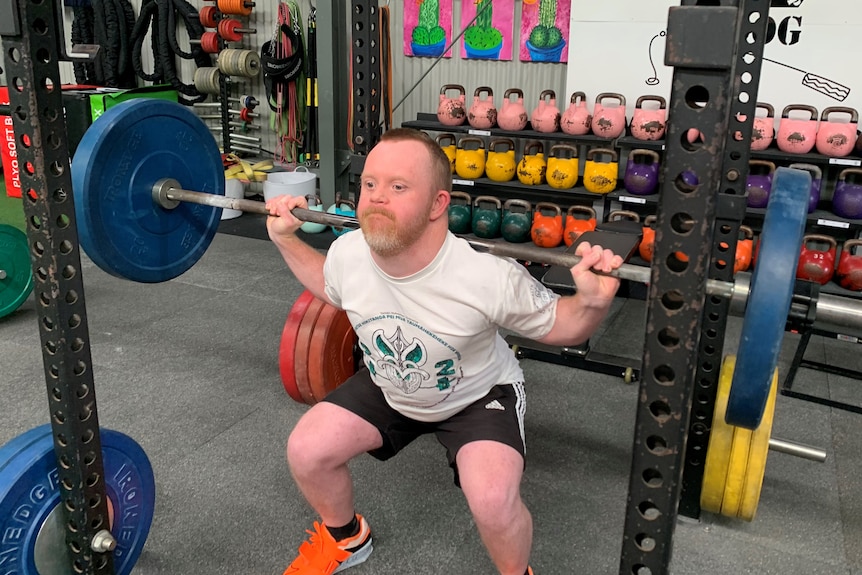 Jack Carroll lifts a barbell in a gym 