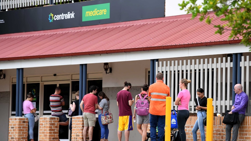 People are seen in a long queue outside a Centrelink office