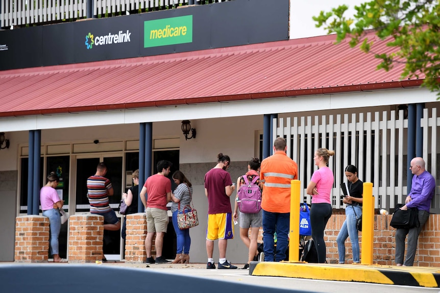 People are seen in a long queue outside a Centrelink office