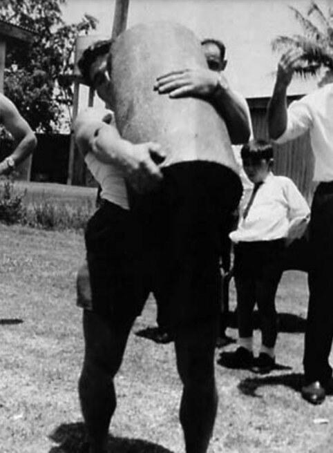 A man lifts a very large cylinder-shaped object.