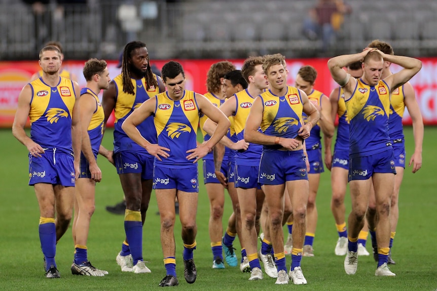 A dejected group of West Coast Eagles players walk off Perth Stadium, after a loss to the Melbourne Demons