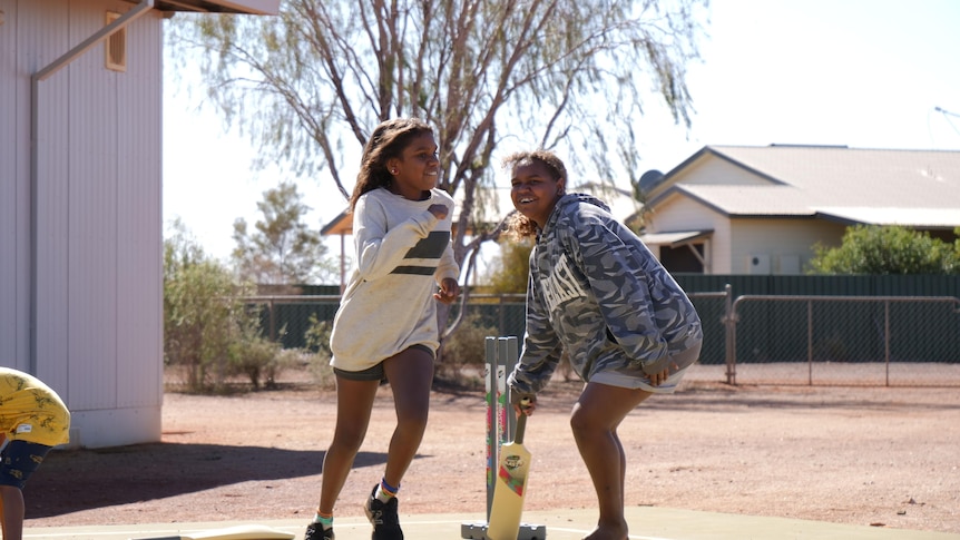 Two young girls with bat and wickets.