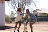 Two young girls with bat and wickets.