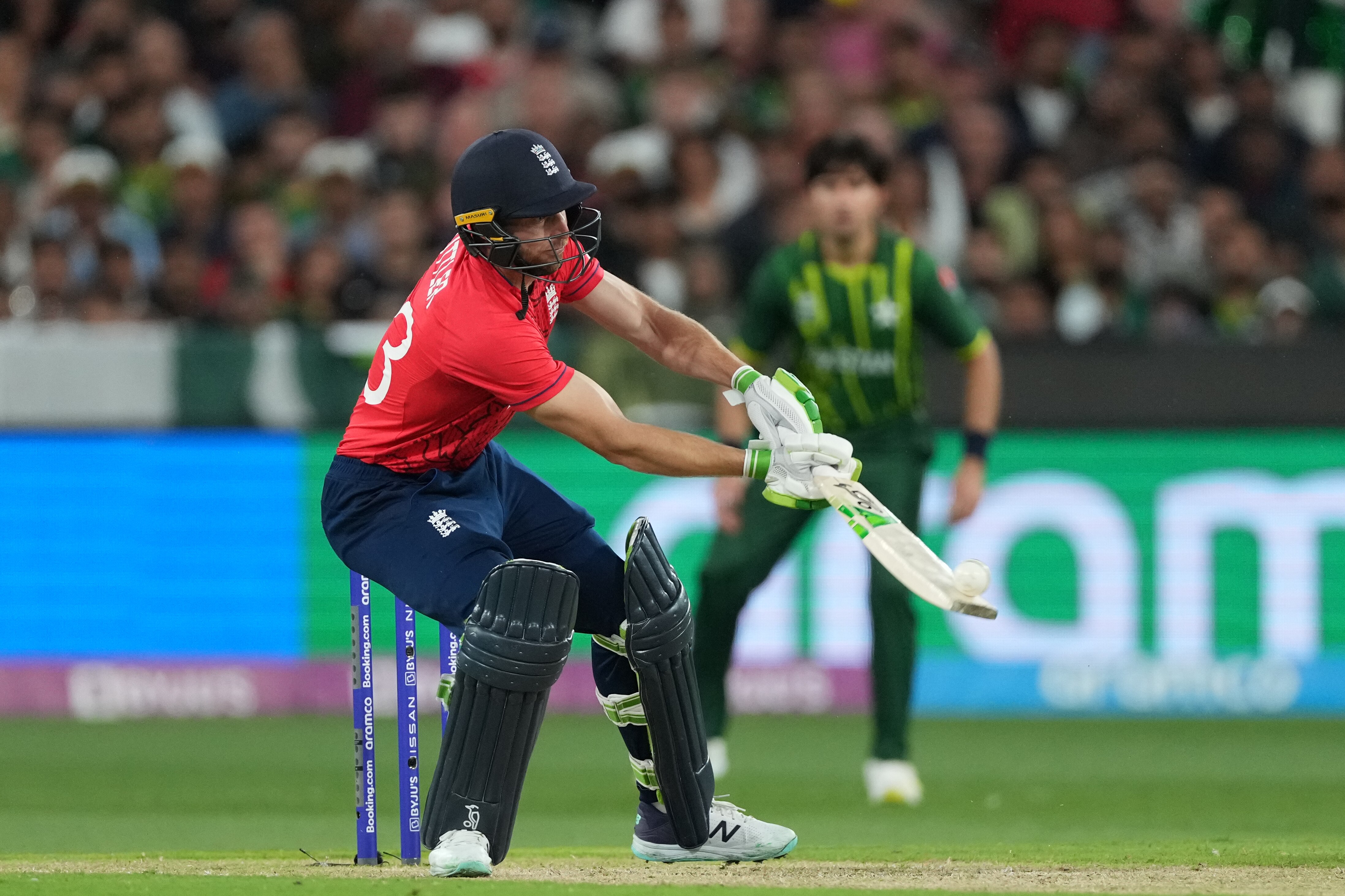 Jos Buttler holds his bat out in front of him and scoops a white cricket ball off the bottom of the bat.