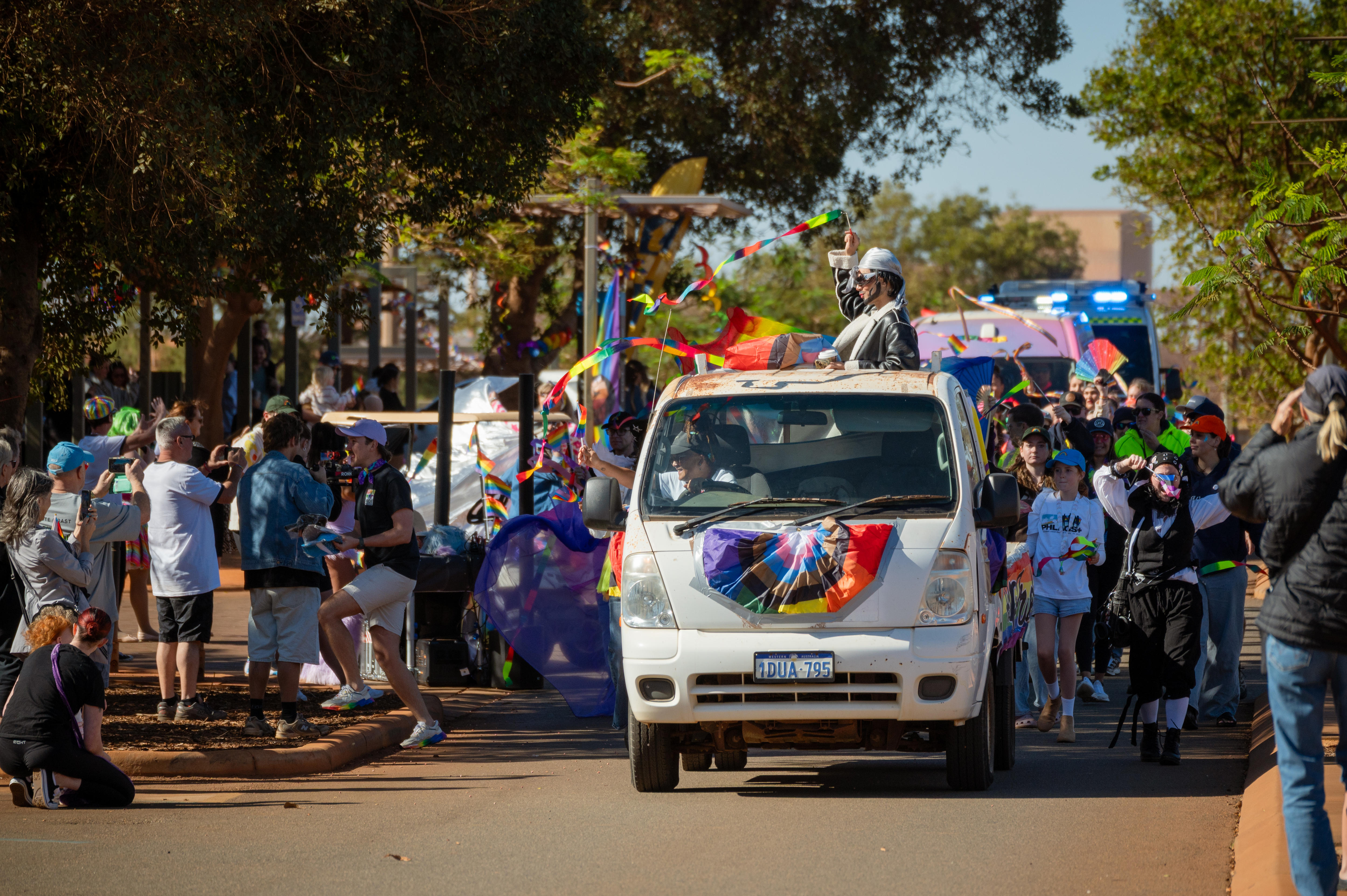 A decorated car with people lining the streets around it.