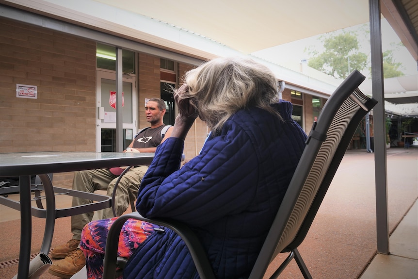 A man and an elderly woman sitting outside at a table.