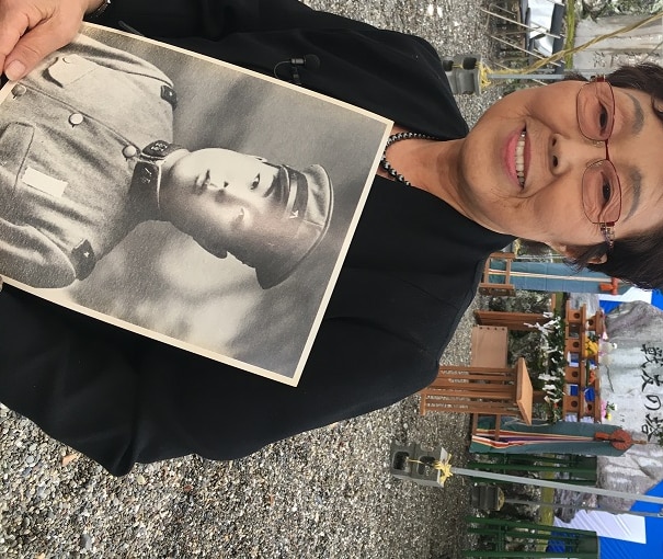 Japanese woman holds old photo of father in uniform