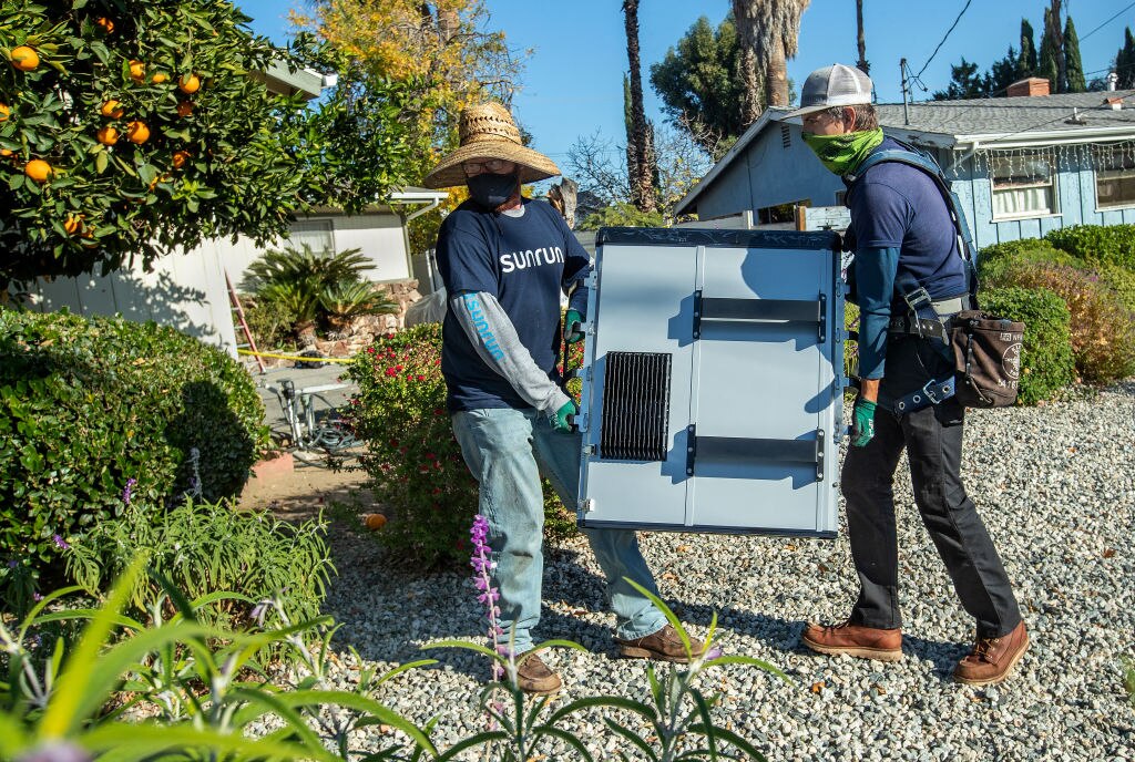 Two men carry a battery.