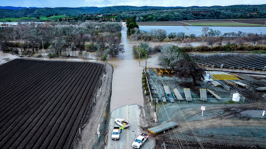 an aerial view of flooding spilling on to a road near houses and farms in California