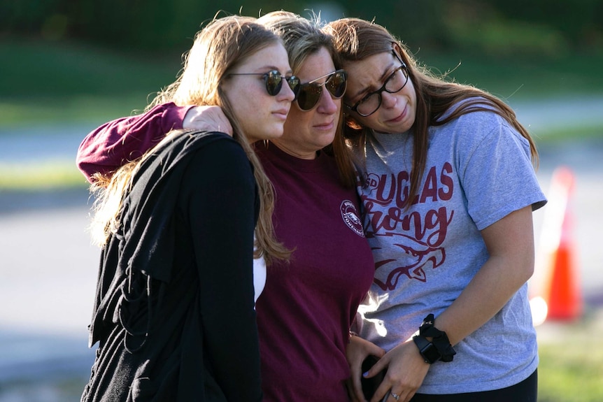 Emma, Cheryl and Sophia Rothenberg embrace at the memorial marking one year since the Parkland, Florida shooting