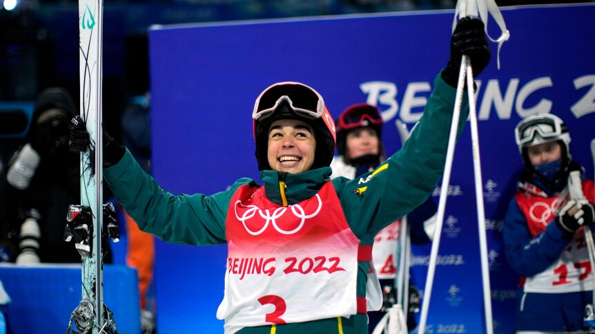 Jakara Anthony holds her skis and poles as she smiles after winning Olympic gold