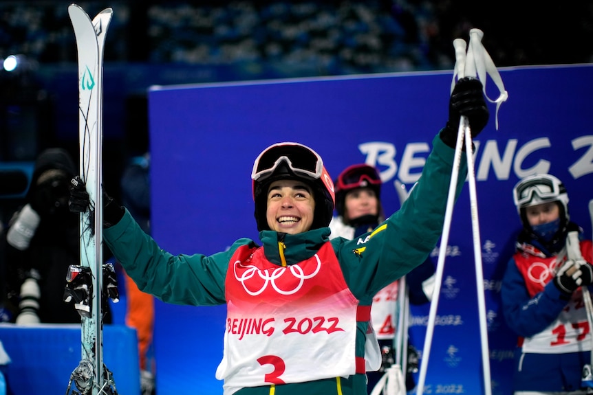 Jakara Anthony holds her skis and poles as she smiles after winning Olympic gold