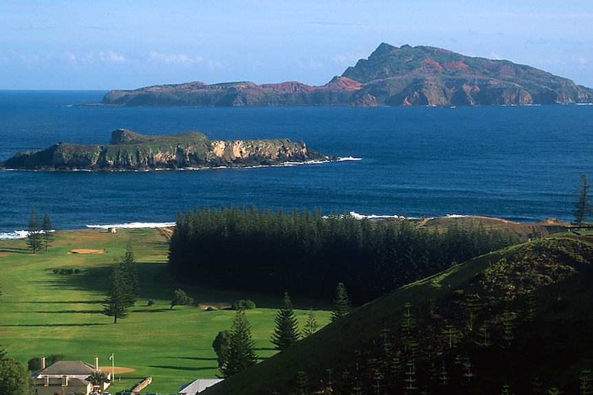 Lovely views of two offshore islands over a lush, green coastline offering a grassy clearing and a forest of trees