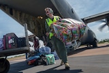 The pilot carries a colourful bag across the tarmac