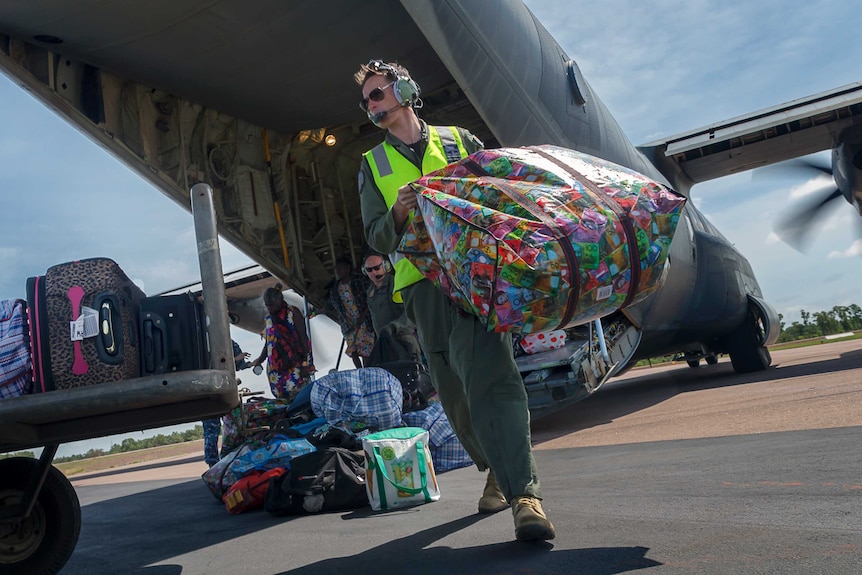 The pilot carries a colourful bag across the tarmac