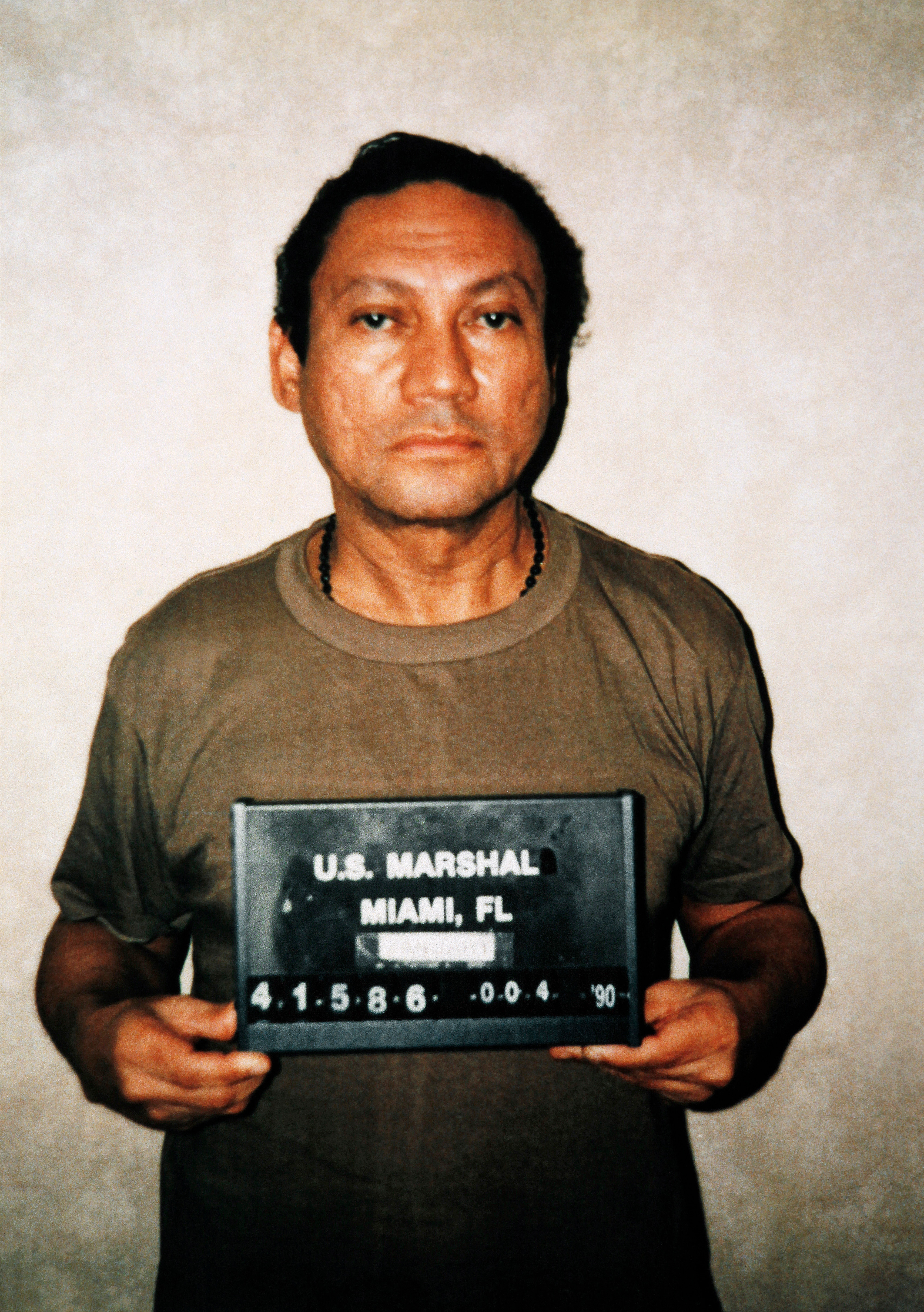 Um homem latino segura uma placa para uma foto. 