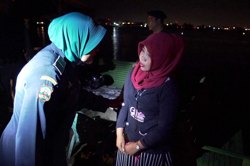 A female officers interviews a woman on the street at night