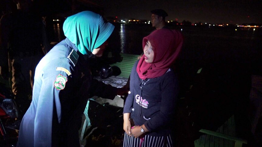 A female officers interviews a woman on the street at night