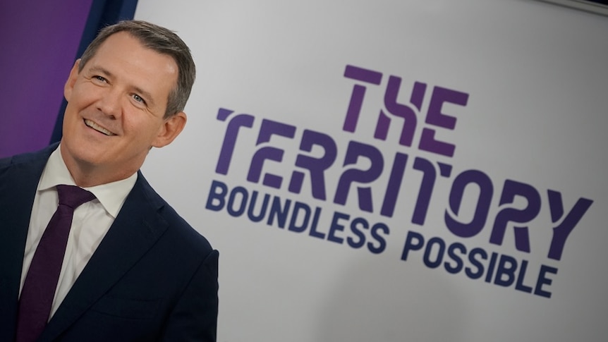 The Chief Minister stands near a sign that reads "The Territory Boundless Possible"