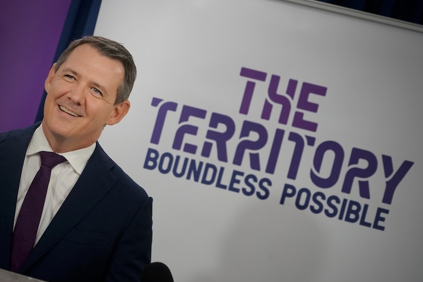 The Chief Minister stands near a sign that reads "The Territory Boundless Possible"