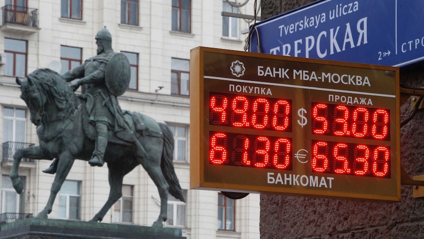 A board showing currency exchange rates, in front of a monument in Moscow