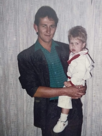 A man holds a small boy in an old photo.