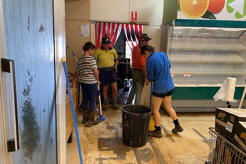 Four people sweeping and cleaning up a flooded shop. 